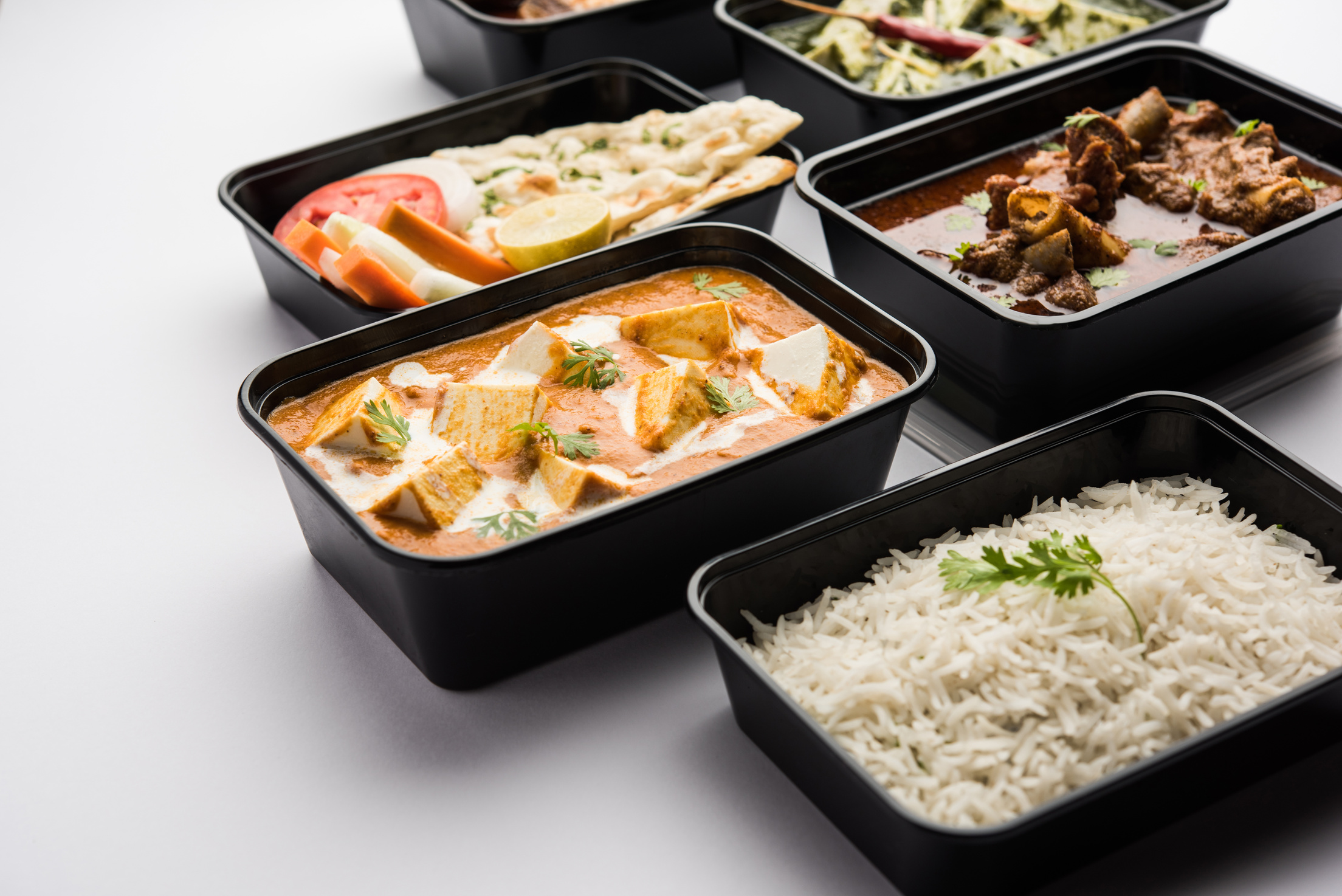 Online food delivery concept for Indian Restaurant showing plastic containers with food